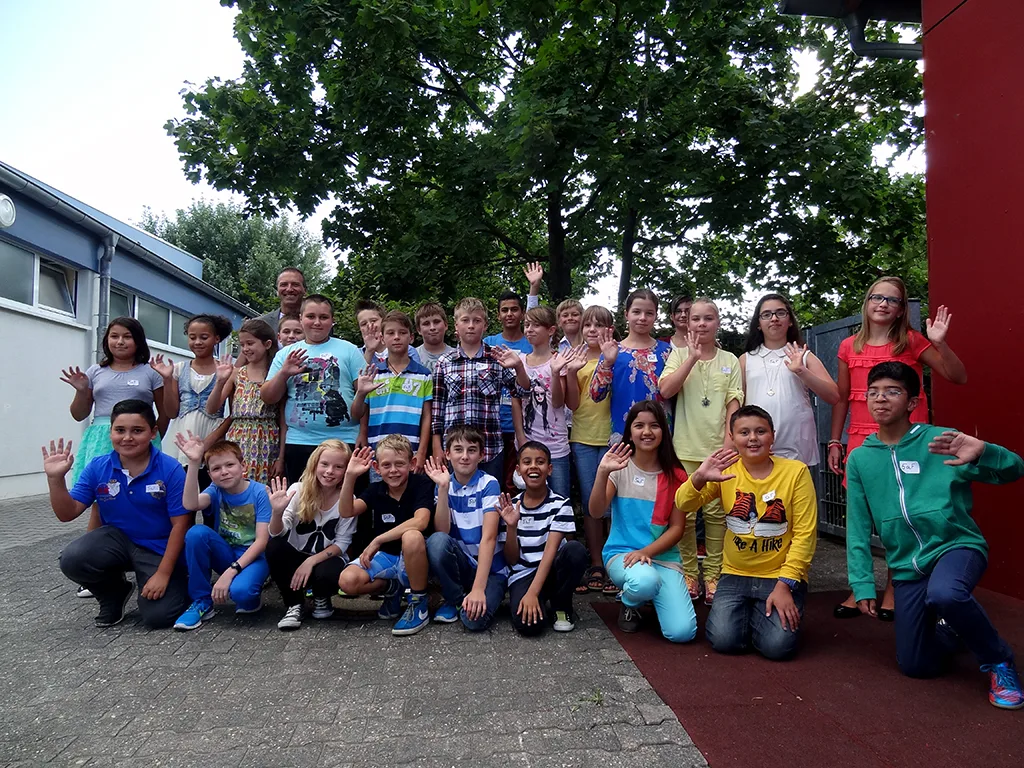 Klassenfoto einer neuen fünften Klasse mit den Klassenleitungen auf dem Schulhof.